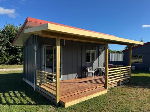 a small house with a deck on the grass at Cosy Cabin Retreat in Makirikiri