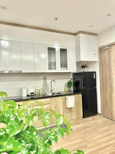 a kitchen with white cabinets and a black refrigerator at Ben's Homestay Ecopark - Onsen Swanlake R3 in Kim Quan