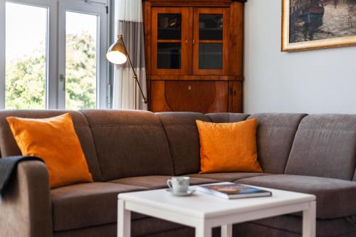 a brown couch with orange pillows and a white table at App Lolita in Kühlungsborn