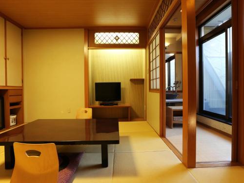 a dining room with a table and a television at Arima Royal Hotel in Kobe