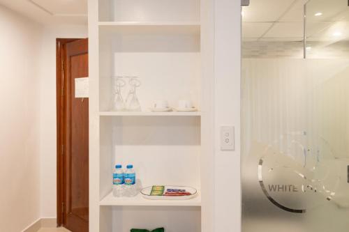 a white book shelf with some items on it at White Lotus Hotel Saigon in Ho Chi Minh City