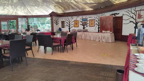a dining room with tables and chairs and a wall with trees at AA Lodge Maasai Mara in Talek