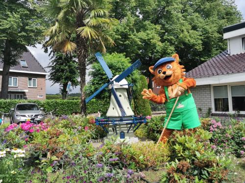 a bear statue in a garden with a windmill at Vakantiepark de Oude Molen in Groesbeek