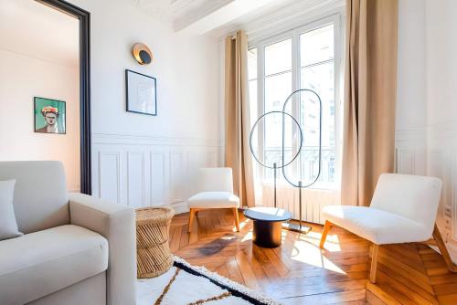 un salon avec des meubles blancs et une grande fenêtre dans l'établissement TBS 322 - Superb apartment with Eiffel Tower view, à Paris