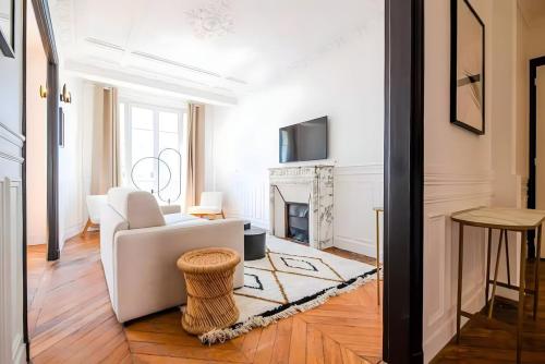 un salon avec un canapé blanc et une cheminée dans l'établissement TBS 322 - Superb apartment with Eiffel Tower view, à Paris