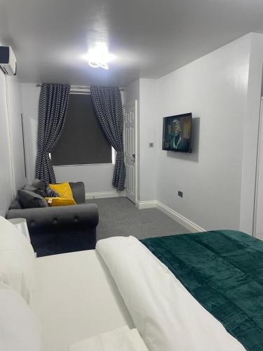 a bedroom with a bed and a couch in a room at Cozy Studio Flat Romford, London in Romford