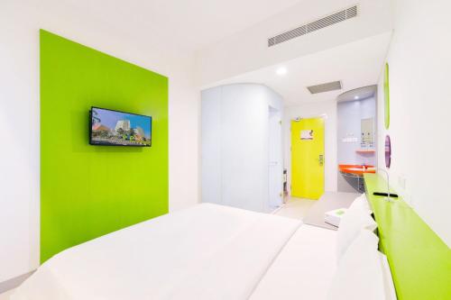 a bedroom with a green accent wall and a white bed at POP! Hotel Kelapa Gading in Jakarta