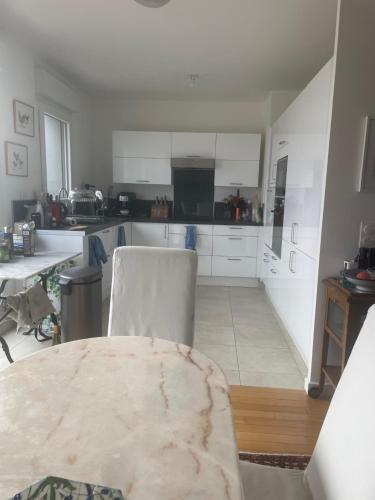 une cuisine avec des armoires blanches et une table dans une pièce dans l'établissement Chambre dans un grand appartement avec terrasse, à Romainville