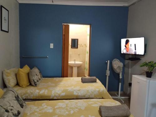 a bedroom with a bed and a flat screen tv at The Rose Guesthouse in Witbank