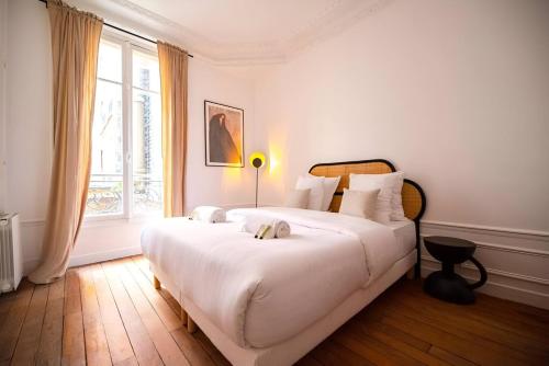une chambre blanche avec un grand lit blanc et une fenêtre dans l'établissement TBS 317 - Apartment close to Eiffel Tower, à Paris