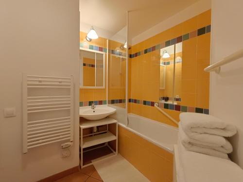 a bathroom with a sink and a tub and a mirror at T1 Bis avec piscine vue golf et montagnes in Arcangues