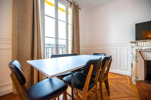 une salle à manger avec une table et des chaises et une fenêtre dans l'établissement TBS 325 - Superb apartment with Eiffel Tower view, à Paris