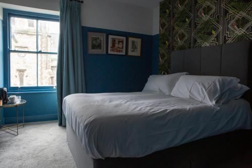 a bedroom with a bed with blue walls and a window at The Crown Rooms in London