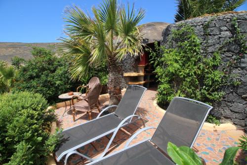 een patio met stoelen, een tafel en palmbomen bij JURTE - Traumhafter Meerblick, beheizter Pool, Sauna, Billiard, Tischtennis, Garten in La Asomada