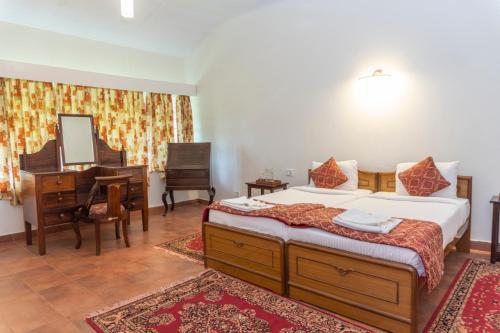 a bedroom with a bed and a desk and a piano at Villa Fair Winds, Sirukundra Estate in Vālpārai