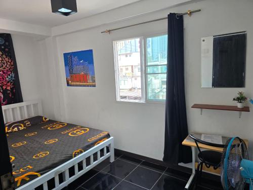 a bedroom with a bed and a desk and a window at Jatujak Bangkok guesthouse R 03-06 in Sathani Bang Su
