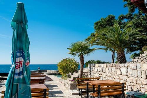 a patio with benches and a umbrella next to the ocean at APARTMANI LUX SEA in Utjeha