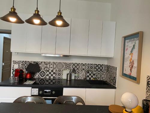 une cuisine avec des armoires blanches et un comptoir noir dans l'établissement Le relais, à Joigny