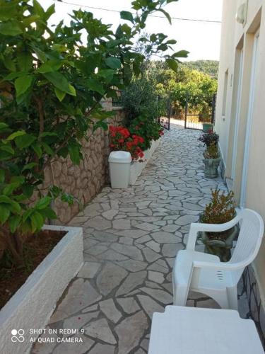 a white chair sitting on a stone walkway at APARTMANI LUX SEA in Utjeha