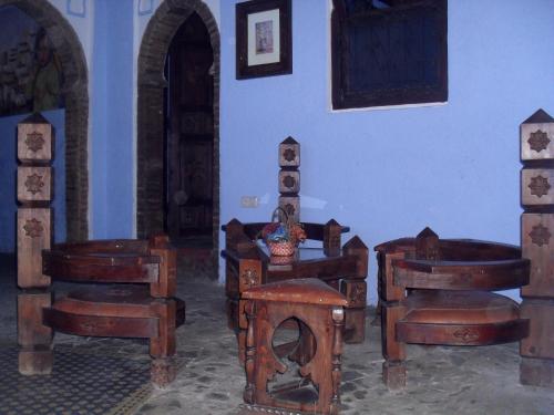 a living room with wooden chairs and a fireplace at Dar Lbakal in Chefchaouene