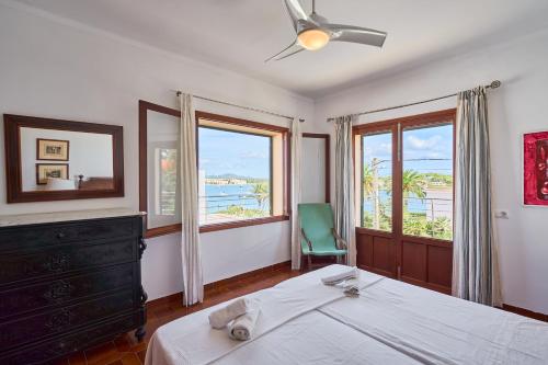 a bedroom with a bed and a chair and windows at Villa Mesquida in Portocolom