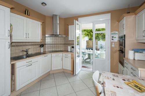 - une cuisine avec des placards blancs et une table à manger dans l'établissement maison proche du marche - 8798, à Soulac-sur-Mer