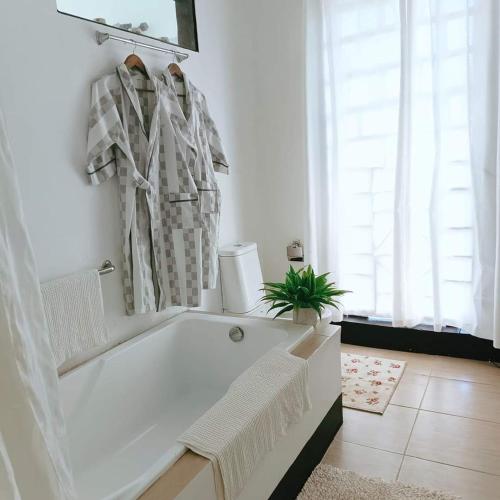 a white bathroom with a tub and a potted plant at RP Botanical Park, Hotel & Resort in Tagbina