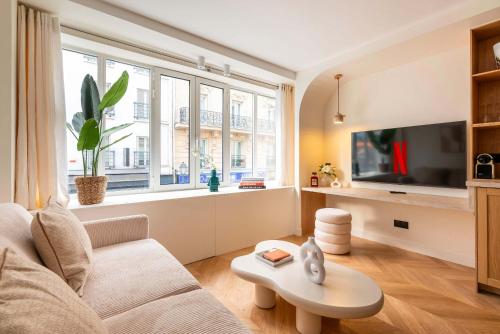 un salon avec un canapé et une grande fenêtre dans l'établissement Montparnasse - Élégance & Confort au Cœur de Paris - Haystia, à Paris