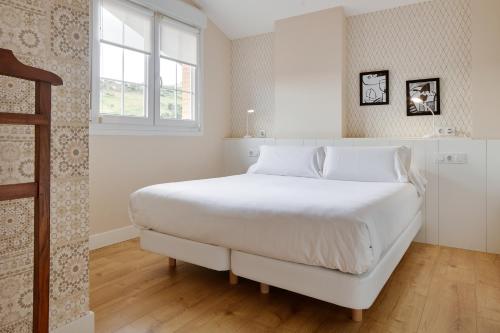a white bedroom with a large bed with white sheets at Hotel Flysch in Zumaia