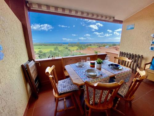 a dining room with a table and chairs and a large window at Costa Rei Panoramic Terrace- Free Parking- BBQ-Netflix in Costa Rei