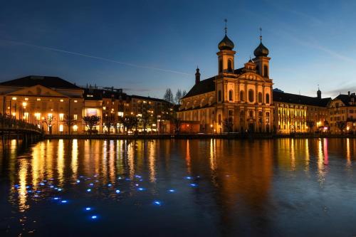 a large building with lights on the water at night at KB CityRooms Self-Check-In in Luzern