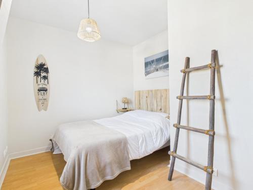 a bedroom with a white bed and a ladder at Jolie maison avec jardin à 450m de la plage pour 8 in Batz-sur-Mer