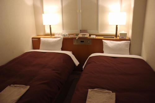 two beds in a small room with two lamps at Country Hotel Takayama in Takayama