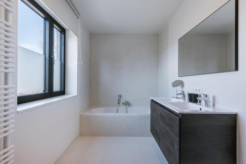 a bathroom with a sink and a bath tub at Maison Atlantis in Nieuwpoort