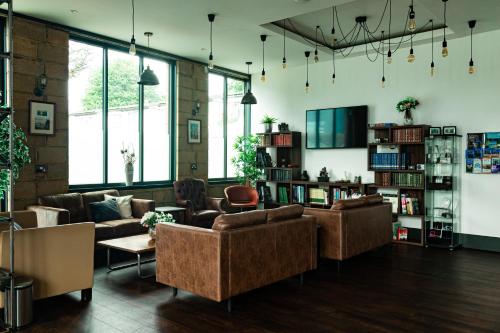 a living room with couches and tables and windows at London City Airport Hotel in London
