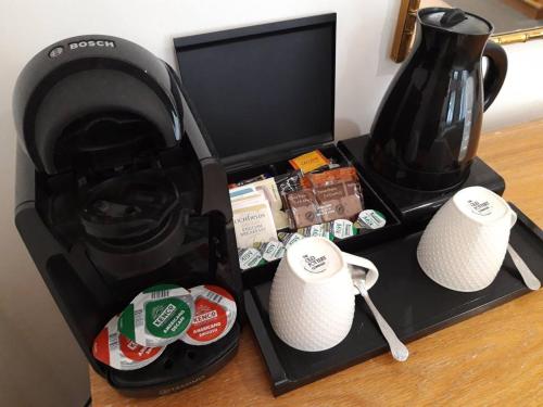 a black coffee maker with two white cups on a table at The Flying Fish Stables in Ilminster