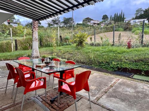 a glass table and red chairs on a patio at Lujosa finca en La Cumbre, Piscina, jacuzzi, WiFi, 5BR in La Cumbre