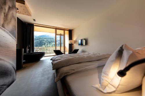 a hotel room with two beds and a balcony at Hotel Arnica Scuol - Adults Only in Scuol