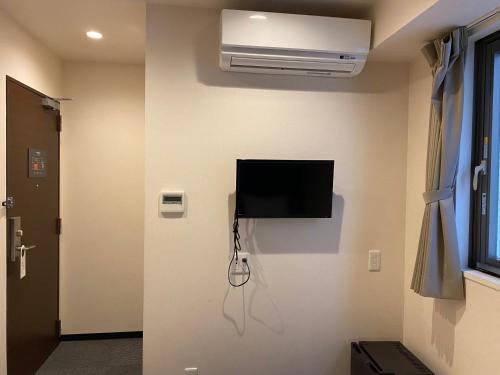a room with a flat screen tv on a wall at Floral Hotel · SakaisuJi-Honmachi Osaka in Osaka