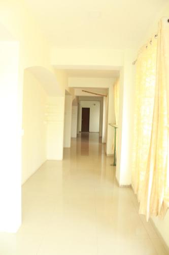 an empty hallway with white walls and a long floor at Hotel Skylark in Vapi