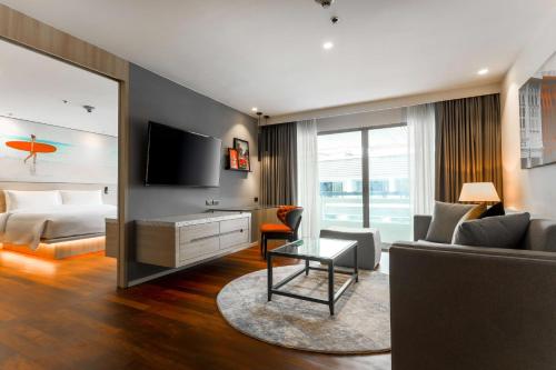 a living room with a couch and a bed and a television at Radisson RED Phuket Patong Beach in Patong Beach