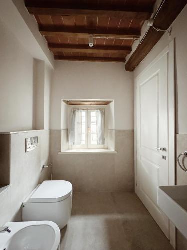 a white bathroom with a toilet and a window at Villa Sofia in Querceta