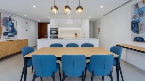 a kitchen and dining room with a wooden table and blue chairs at Pine Cliffs Village in Albufeira