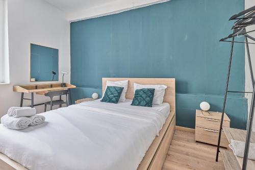 a bedroom with a large bed with a blue wall at Château Émeraude, T2 hypercentre, Terrasse, Charme et détente in Château-Thierry