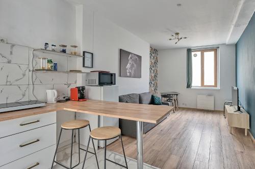 une cuisine avec une table et des tabourets dans une pièce dans l'établissement Château Émeraude, T2 hypercentre, Terrasse, Charme et détente, à Château-Thierry