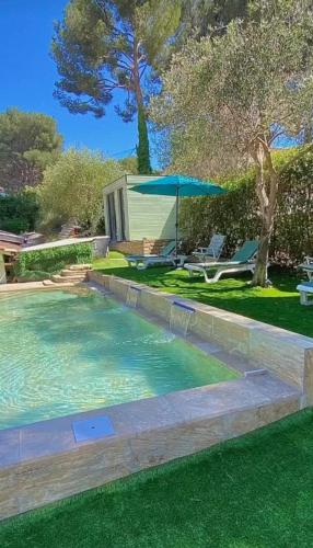 - une piscine dans une cour avec une table et un parasol dans l'établissement Brooklyn Studio Rose, à Sanary-sur-Mer