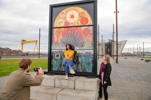 a man taking a picture of a woman sitting in a painting at Ocho Homes by Eight Continents in Belfast