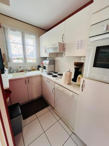 Elle comprend une petite cuisine avec des placards blancs et un réfrigérateur. dans l'établissement la maison de Luna, cayeux sur mer, baie de somme, à Cayeux-sur-Mer