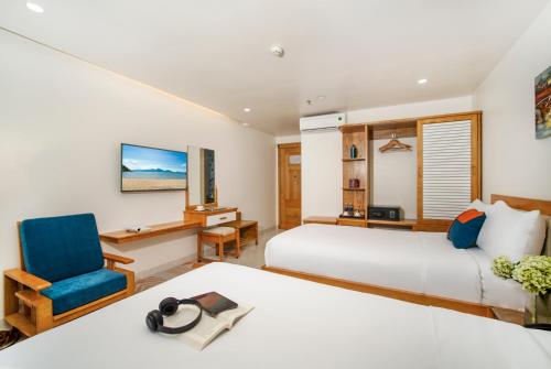 a hotel room with two beds and a chair at Ocean Bliss Hotel - Free Sauna in Da Nang
