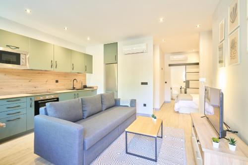 un soggiorno con un divano blu e una cucina di Alojamiento Centro Histórico Universidad S15 a Salamanca
